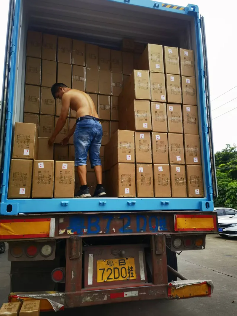 A loader stacking cartons against the corrugated wall of a blue container